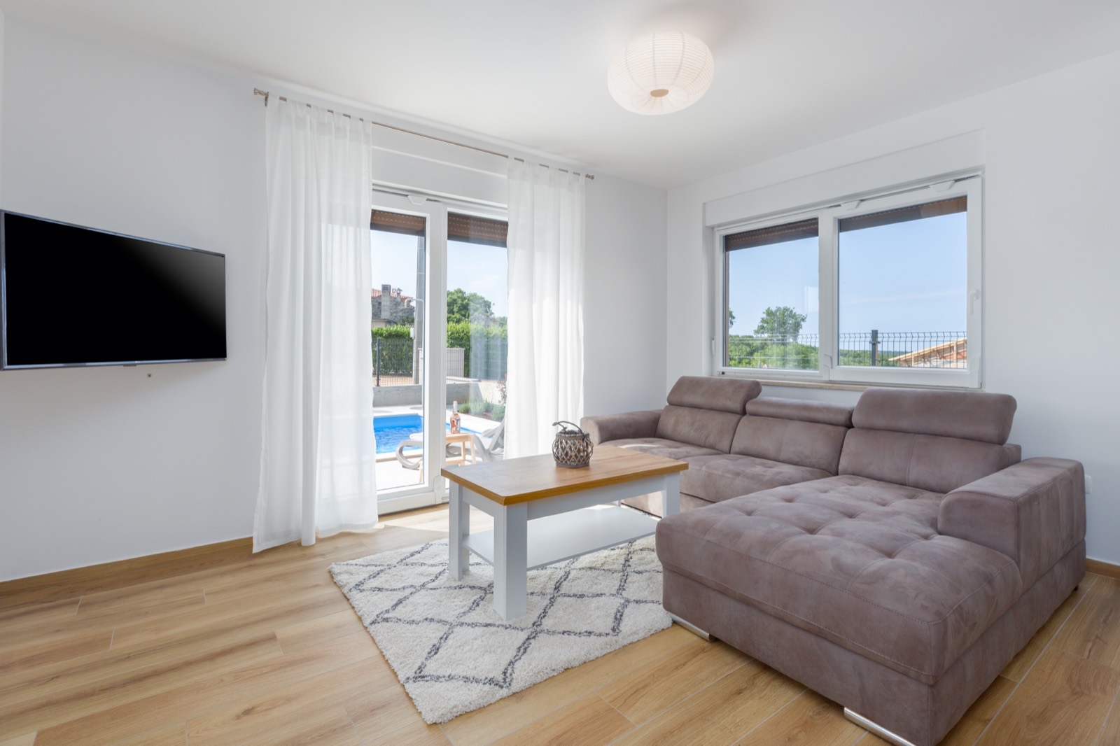 Living room with corner sofa and doors opening onto the pool terrace